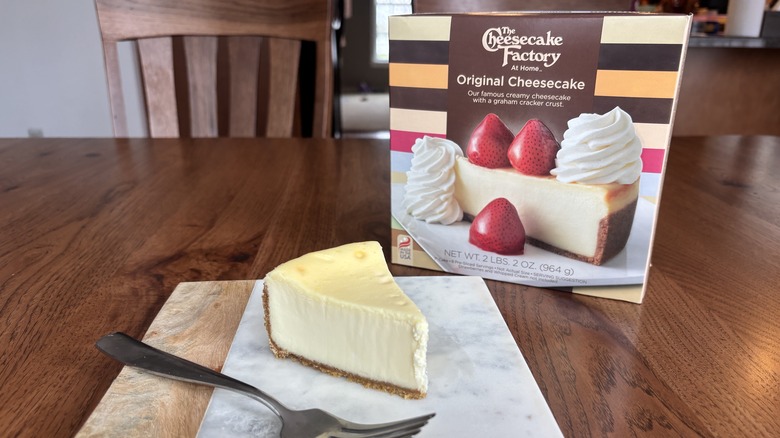 slice of cheesecake on plate with fork and cheesecake box