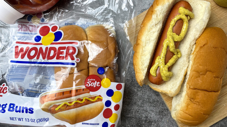 A bag of Wonder Classic Hot Dog Buns next to a hot dog with mustard on it