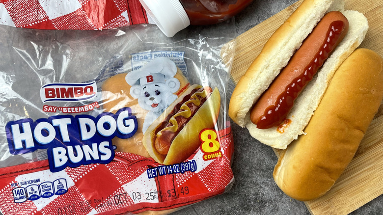 A package of Bimbo hot dog buns next to a hot dog with ketchup