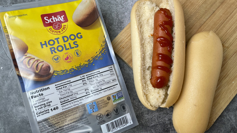 A package of Schar gluten-free hot dog rolls next to a hot dog with ketchup