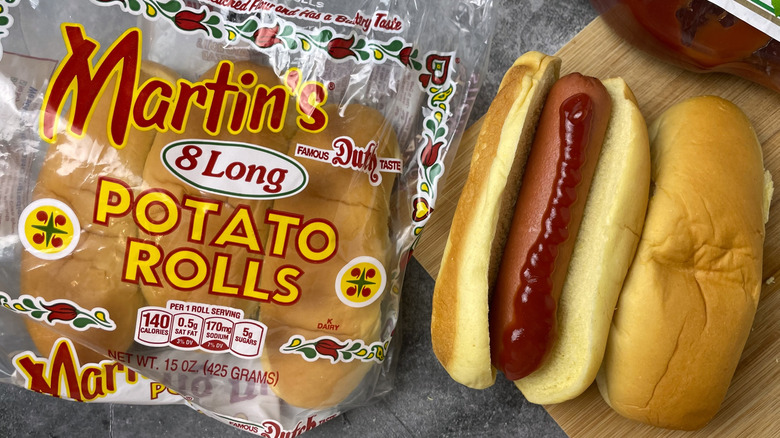 A package of Martin's long potato rolls next to a hot dog with ketchup on it