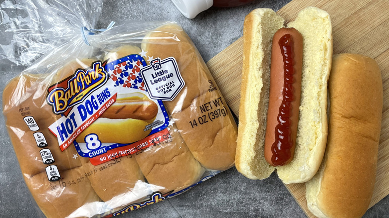A package of Ball Park hot dog buns next to a hot dog with ketchup on it