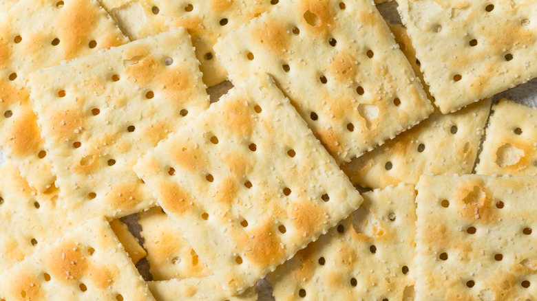 A close-up of saltine crackers piled on top of each other.
