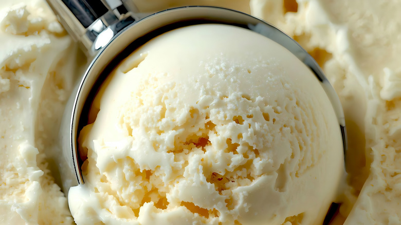 Metal scoop digging into vanilla ice cream.