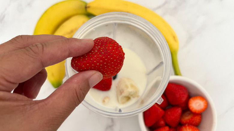 adding fresh strawberries to blender