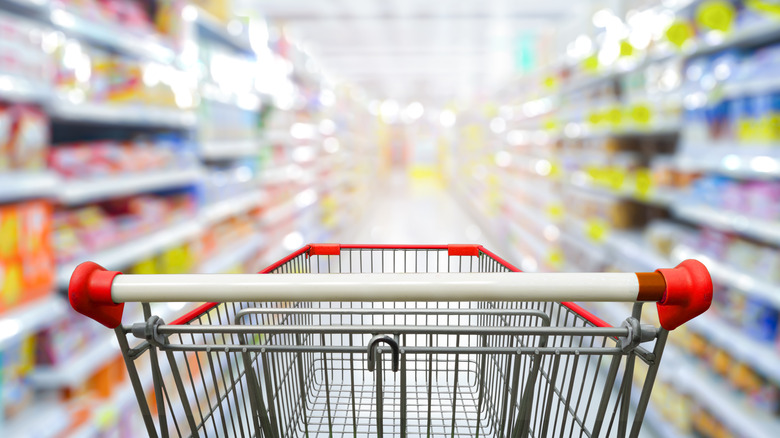 empty shopping cart facing supermarket aisle