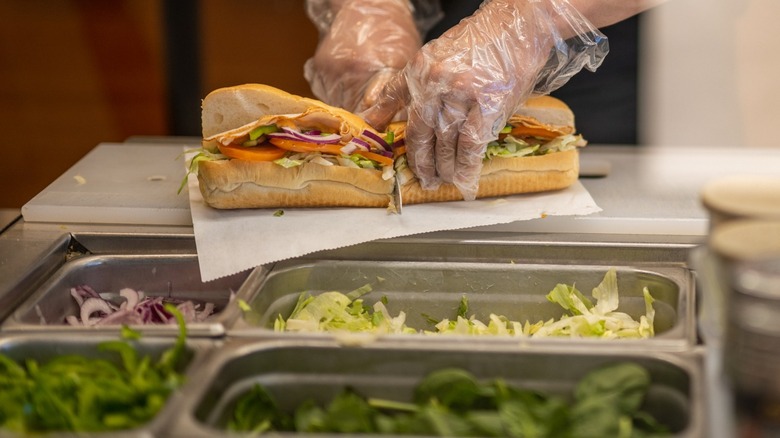 Subway employee cutting sandwich