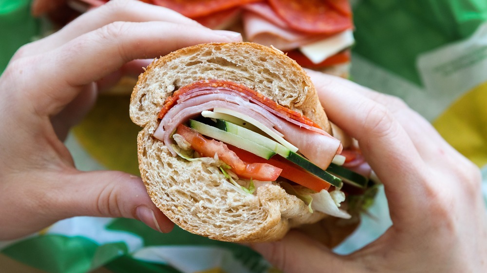 Hands holding a Subway sandwich