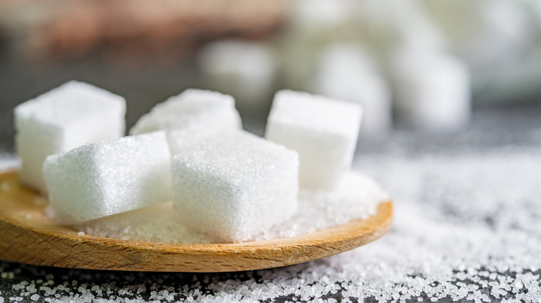 White sugar cubes on wooden spoon