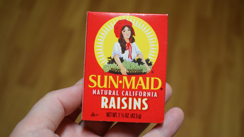 Hand holding a red box of Sun-Maid raisins