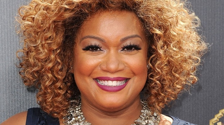 Sunny Anderson smiles with purple lipstick