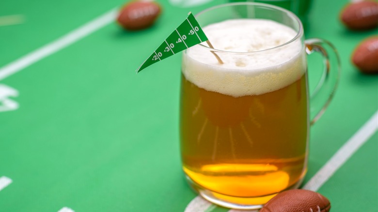 A mug of beer on a miniature football field with mini footballs