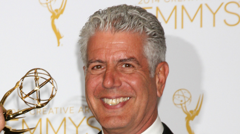 a happy Anthony Bourdain holding an Emmy