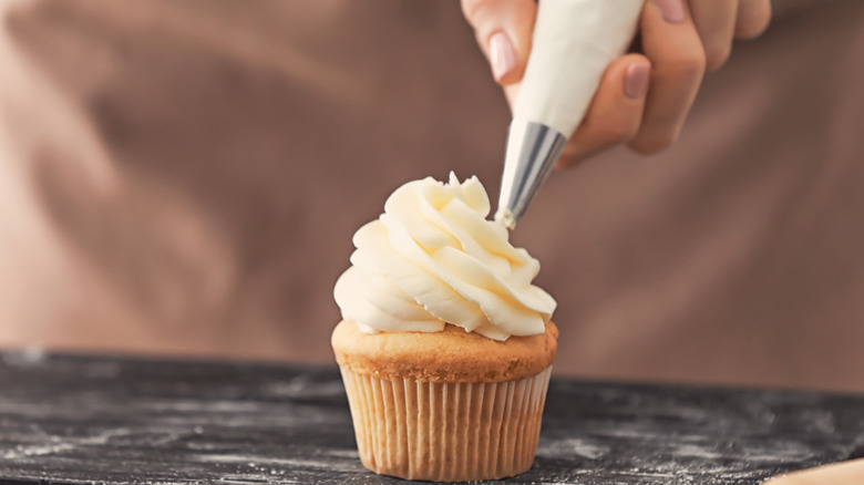 Woman frosting a cupcake 