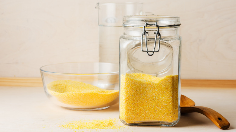 Stoneground cornmeal in a bowl with a jar half full of cornmeal next to it.