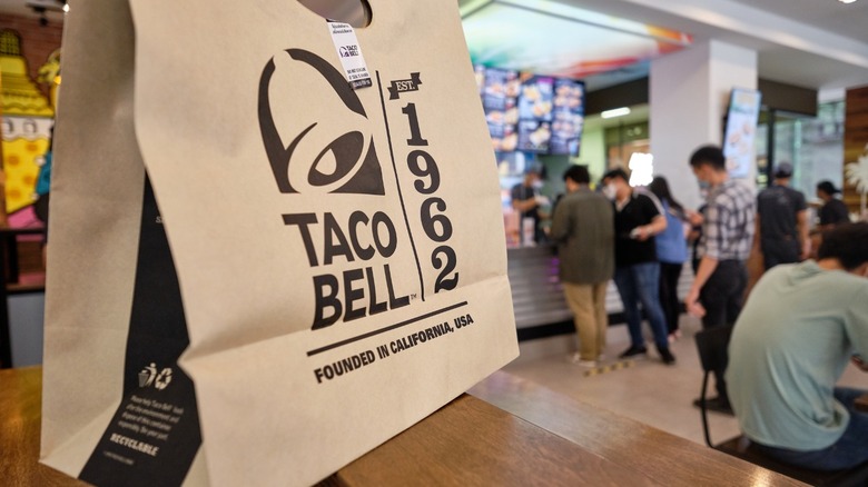 Taco Bell bag with line of customers in the background