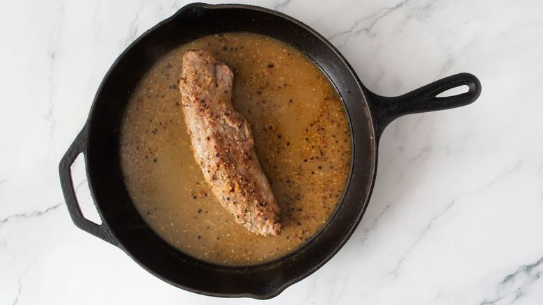 Roast pork tenderloin with pan drippings in skillet