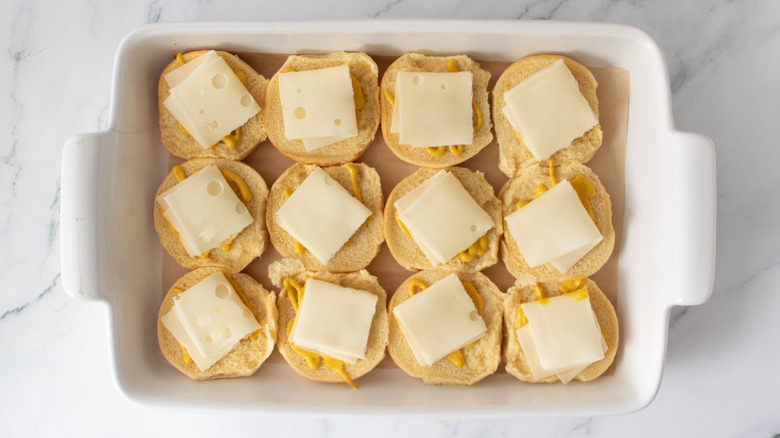 Buns in baking dish with mustard and cheese