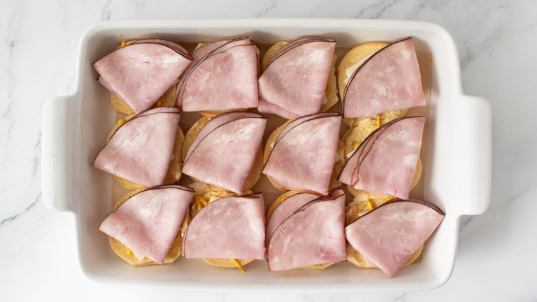 Sliders layered with ham in baking dish