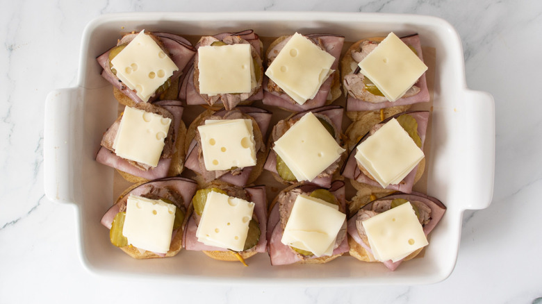 Uncapped pork sliders topped with cheese in baking dish