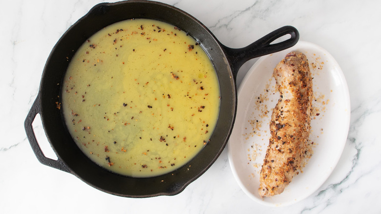 Orange juice mixture in skillet next to tenderloin on plate