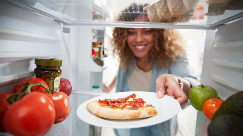 Woman getting pizza out of fridge