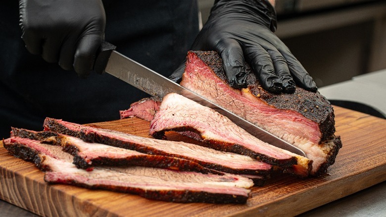 Hands with black gloves slicing brisket