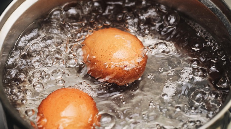 Two brown eggs being boiled in water