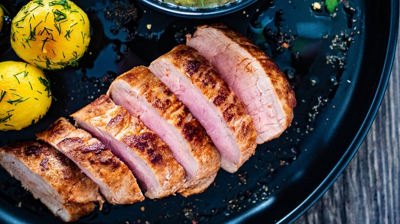 Grilled pork tenderloin on a plate with baby potatoes and dill