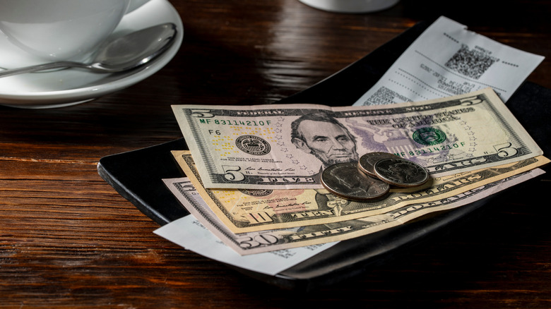 Restaurant bill with sixty dollars cash and some change placed on top
