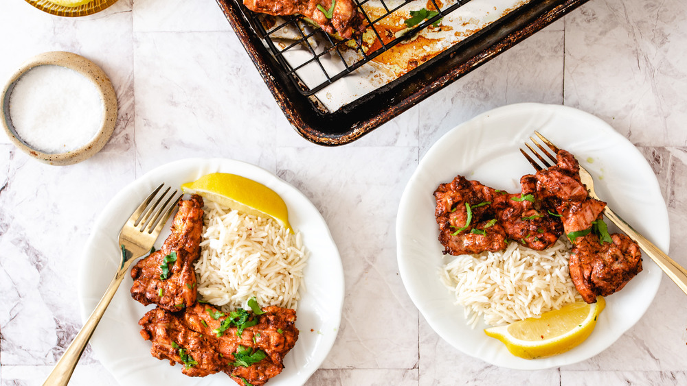 tandoori chicken on plates and on baking sheet with lemon slices