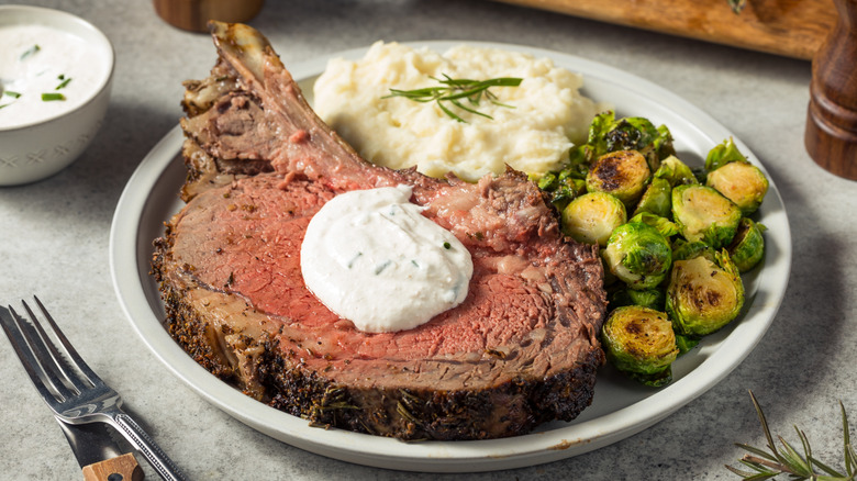 Prime rib with horseradish sauce and sides on plate