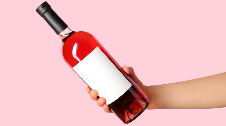 hand holding pink wine bottle