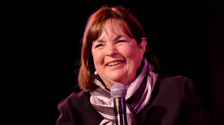 Ina Garten holding a microphone and laughing on stage at an event