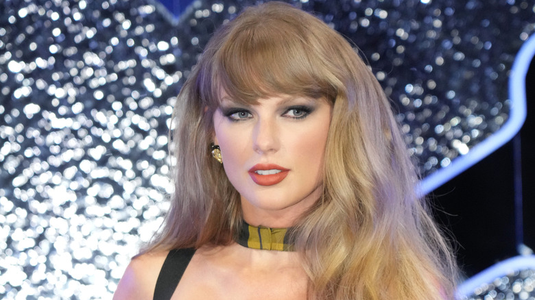 Taylor Swift with her hair down, wearing a plaid choker necklace