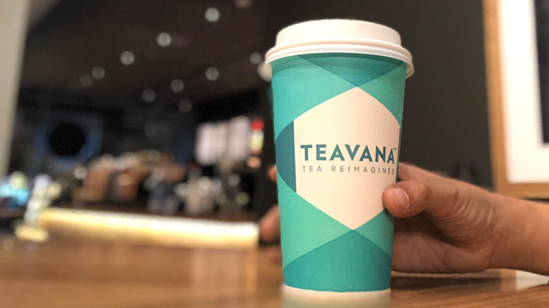 Person holding paper cup with the word Teavana