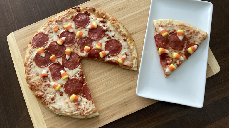 Tombstone pepperoni and candy corn pizza on a board with a slice on a plate