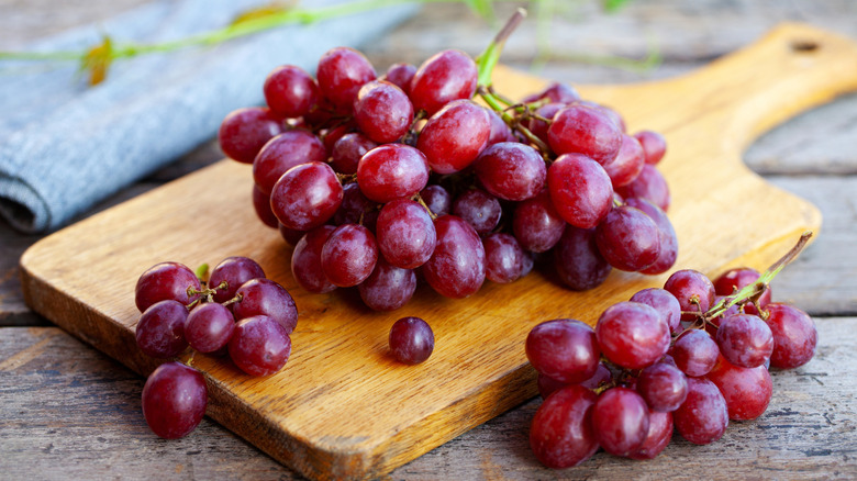 Red grapes on stem on a cutting board