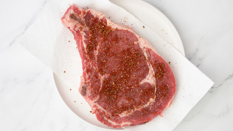 seasoned ribeye steak on paper towel lined plate