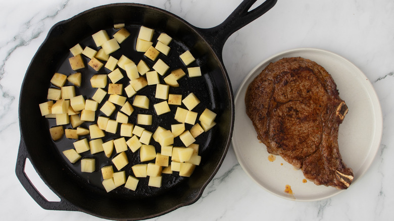 cubed potatoes cooking in skillet