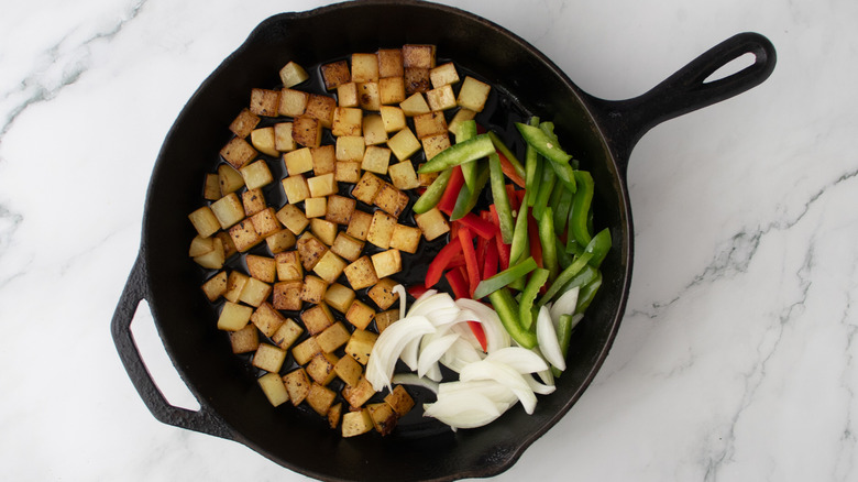 potatoes wiht raw veggies in skillet
