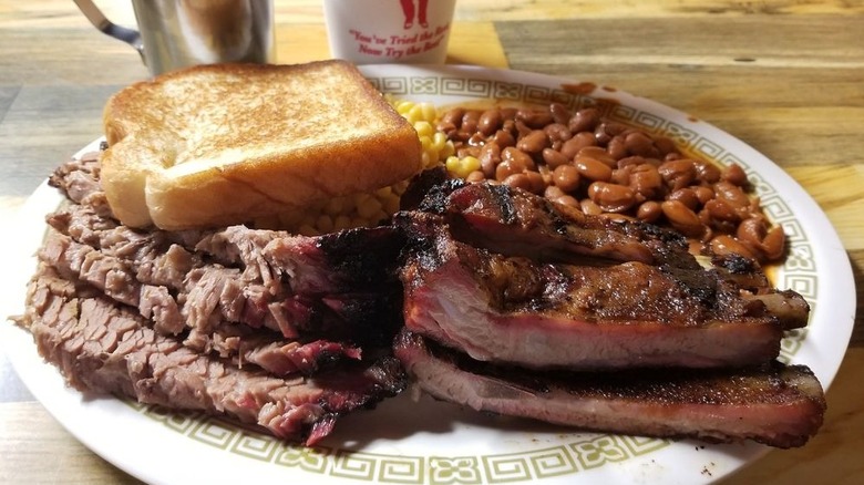 Brisket, ribs, white bread, and beans piled on paper plate.