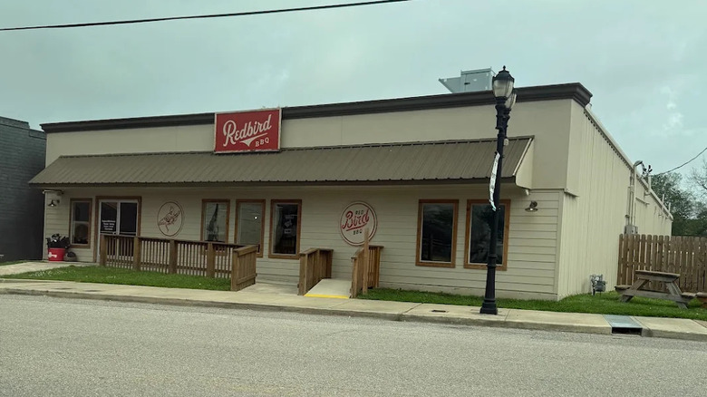 A small building with a red sign that says Redbird BBQ in white cursive font.
