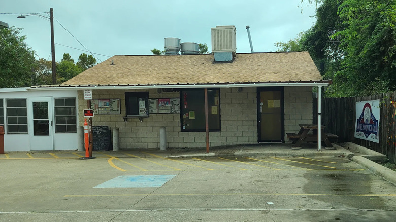 A small, rundown building with large vents on the roof.