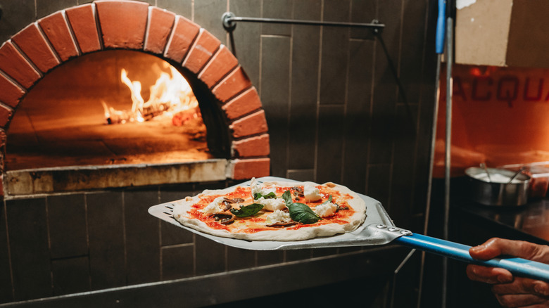 Pizza going into wood fire oven