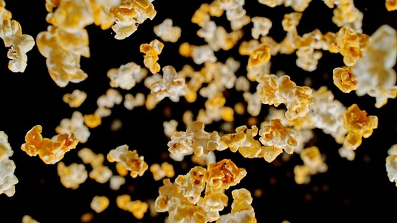 Popped popcorn falling against black background