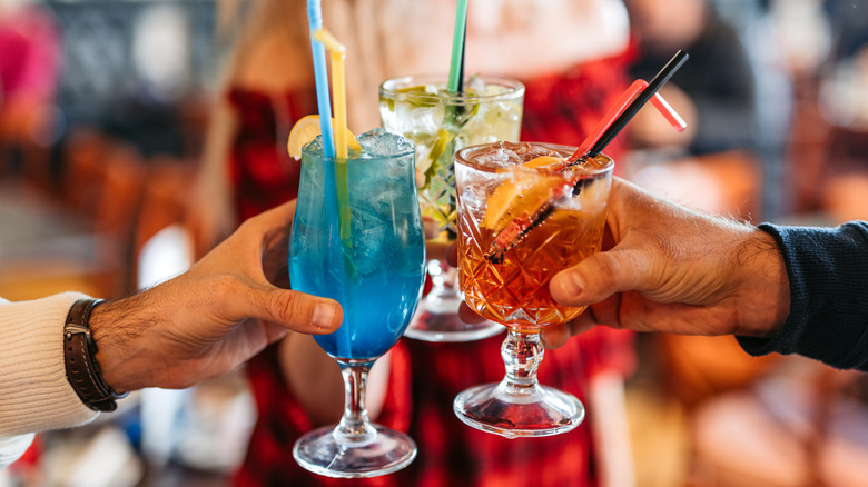 Friends cheering with a variety of cocktails with straws