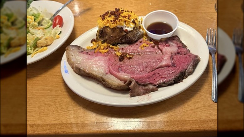 A plate with prime rib, baked potato, and sauce at Texas Roadhouse restaurant.