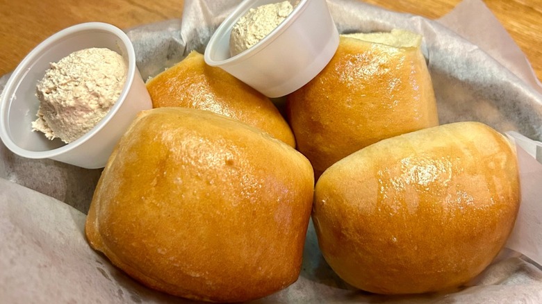 Fresh dinner rolls with honey cinnamon butter in tubs on a table at Texas Roadhouse.