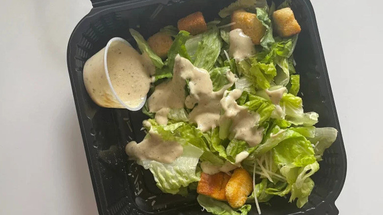 Outback Caesar salad in a to-go container with dressing on the side
